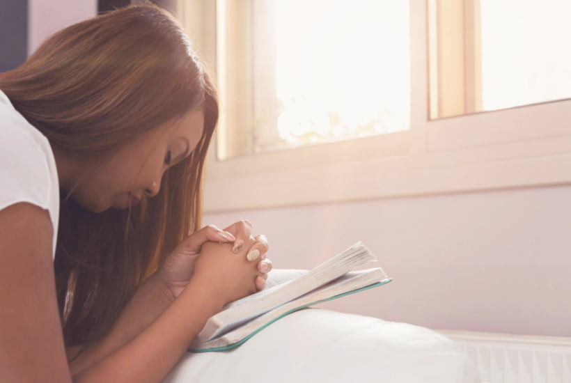 Woman praying with head bowed. If you need some encouragement or inspiration to keep going in your faith, this list of Bible verses about God’s faithfulness is for you.